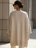 Beige oversized poncho from back view with ribbed hem and relaxed fit