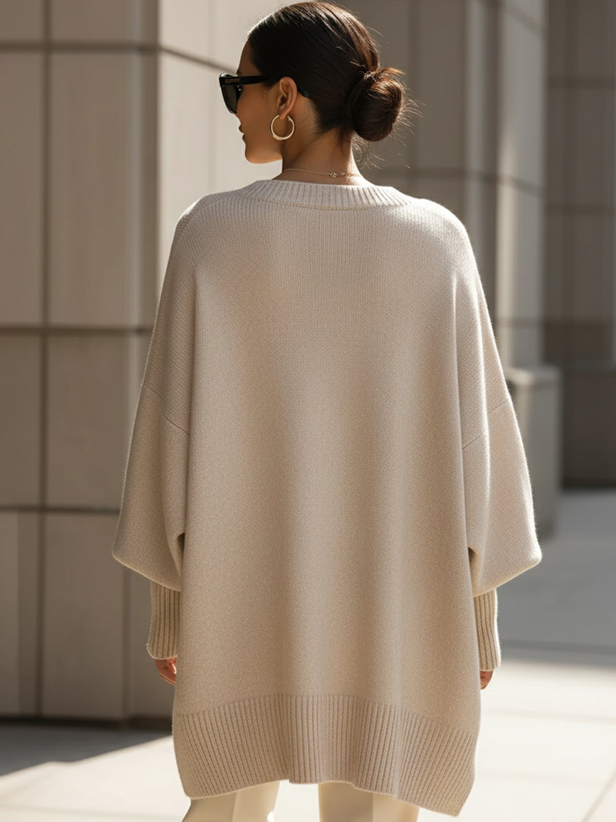 Beige oversized poncho from back view with ribbed hem and relaxed fit