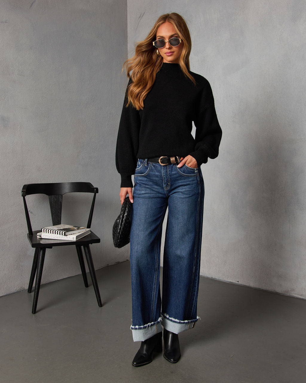 Black mock neck knit sweater with long sleeves and relaxed fit, styled with jeans.