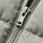 Light grey puffer jacket zipper close-up with metal pull and fabric trim