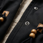 Black lined-hood parka jacket detail with snap buttons and leather toggles