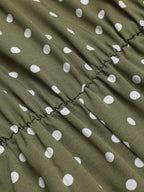 Green polka dot fabric close-up with gathered seam and ruffled edge