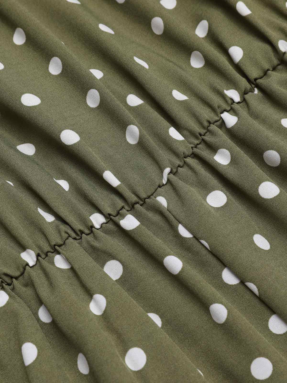Green polka dot fabric close-up with gathered seam and ruffled edge