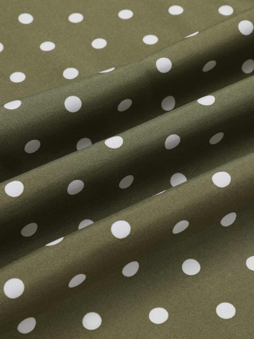 Green polka dot woven fabric close-up with smooth drape