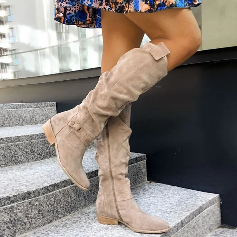 Women’s beige suede ankle boots with stacked heel and buckle detail at shaft