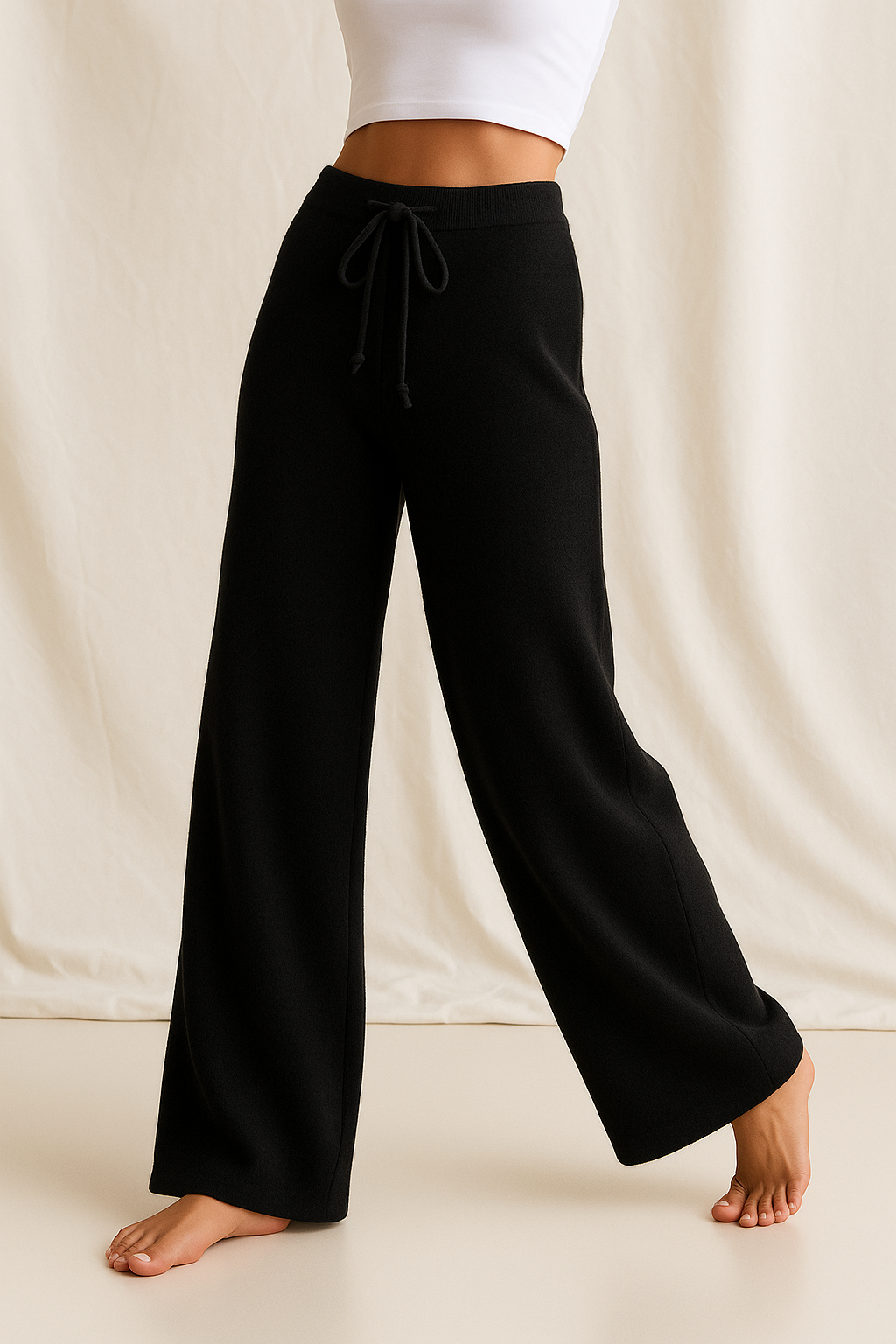 Black high-waisted wide-leg lounge pants with drawstring, worn with bare feet.