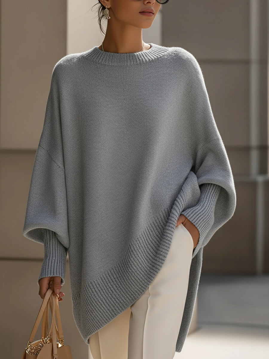 Grey oversized knit poncho with wide sleeves and draped asymmetric hem