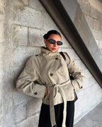 Light khaki cropped trench coat with belted waist and buttoned flap pockets