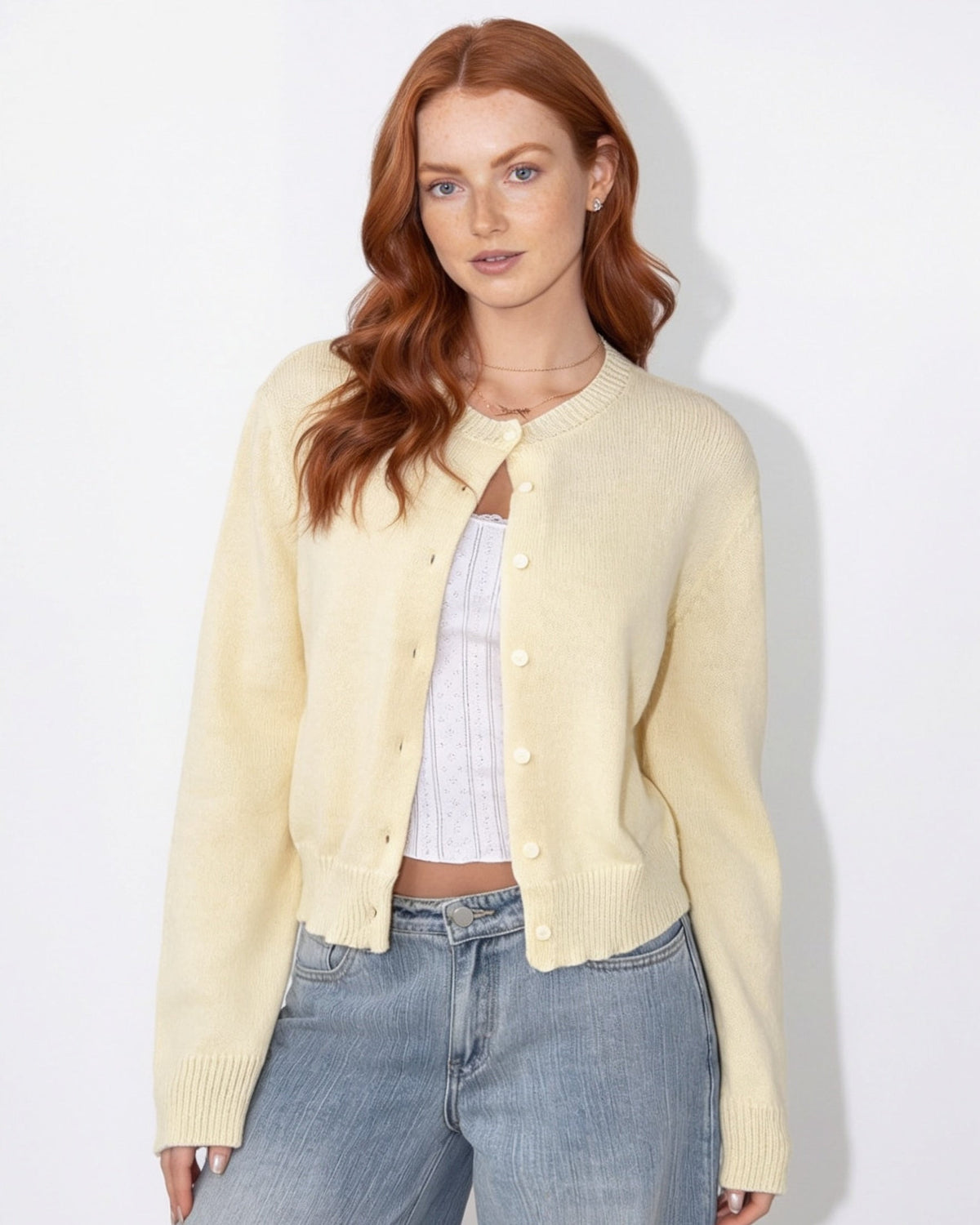 Light cream cropped knit cardigan with round neck and button-front, long sleeves.