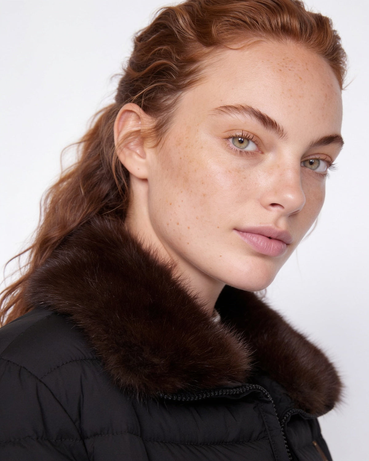 Dark brown faux fur collar on a black puffer jacket with zip edge