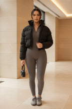 Black cropped puffer jacket with funnel collar and zip front, worn over base layer