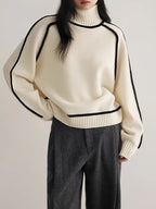 Cream turtleneck knit sweater with black piping details and ribbed hem