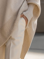 Beige knit poncho detail with ribbed cuff and draped side opening