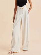 Cream wide-leg tailored pants with tailored front crease and gold waistband button