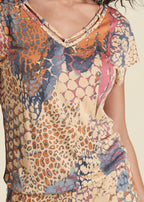 V-neck romper close-up: multicolor abstract orange print and scoop neckline