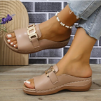 Women’s beige open-toe wedge sandals with metallic buckle strap and textured sole.