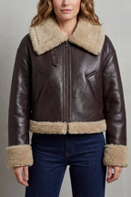 Dark brown cropped aviator jacket with tan fleece collar and trim; front zip and pocket flaps.