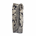 Leaf-pattern pareo in black and beige, tie front, tassel-trim hem; worn over bikini top