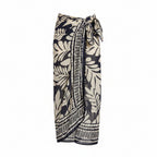 Leaf-pattern pareo in black and beige, tie front, tassel-trim hem; worn over bikini top