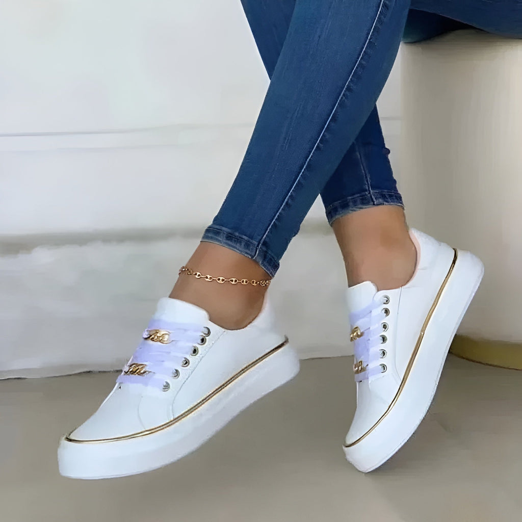 White women's orthopedic sneakers with gold piping and lace-up front, plus gold link ankle strap