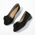Black suede ballerina flats with a bow detail and slip-on design