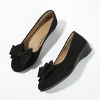 Black suede ballerina flats with a bow detail and slip-on design