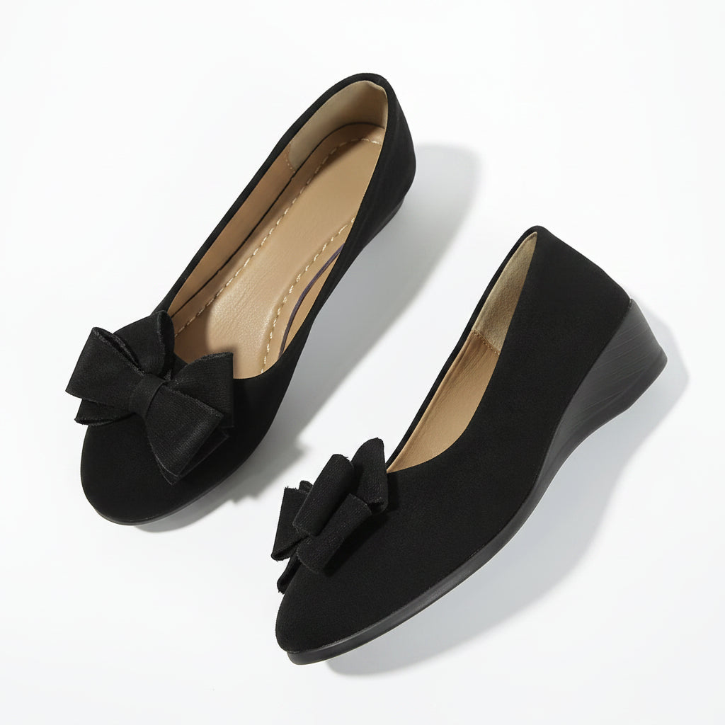 Black suede ballerina flats with a bow detail and slip-on design