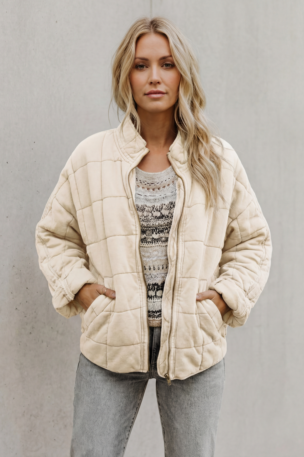 Cream quilted women’s jacket with front zipper and stand collar.