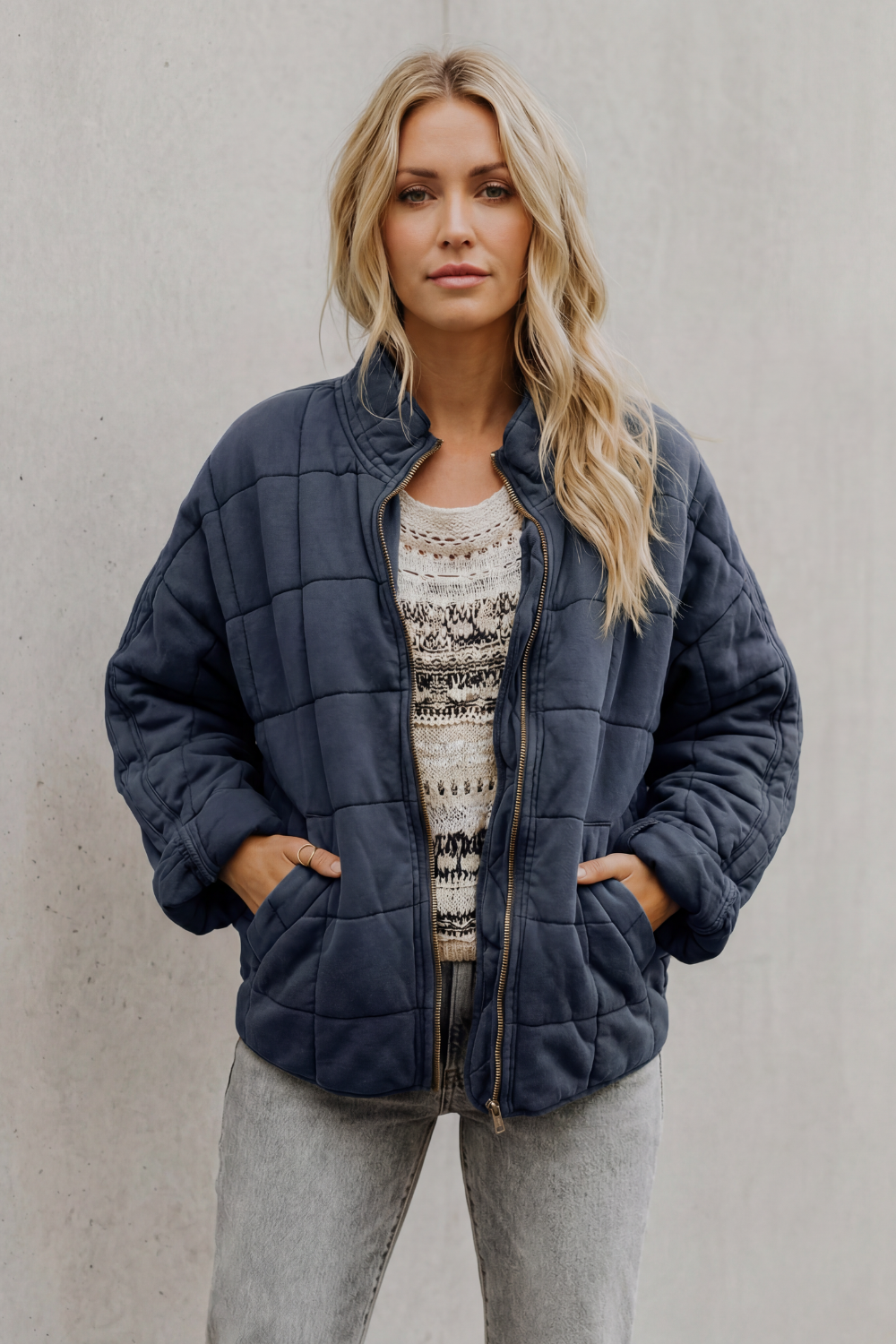Navy quilted women’s jacket with front zipper and stand collar, side pockets.