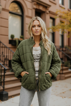 Dark green quilted women’s jacket with front zipper and stand collar.