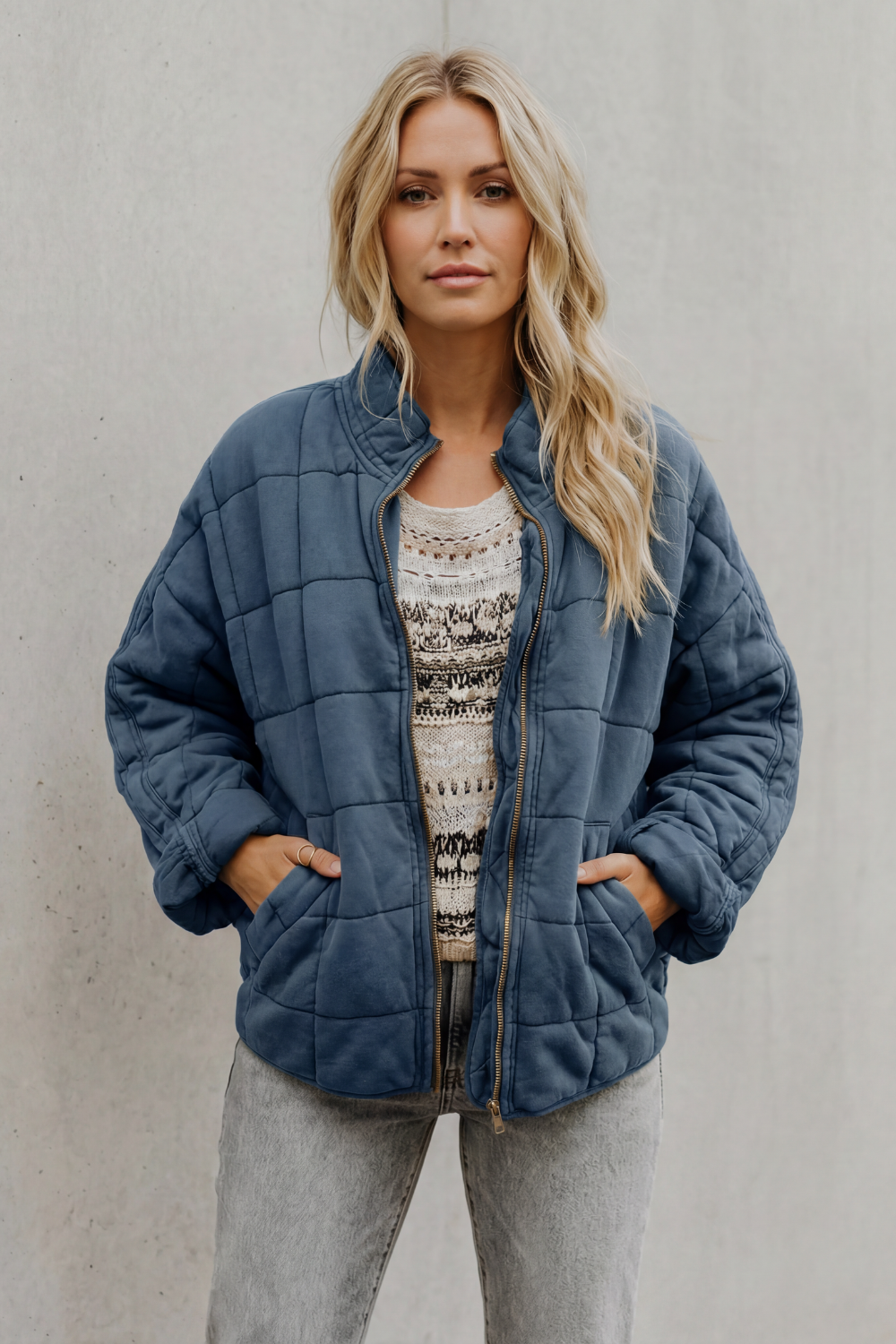 Blue quilted women’s jacket with front zipper and stand collar, side pockets.