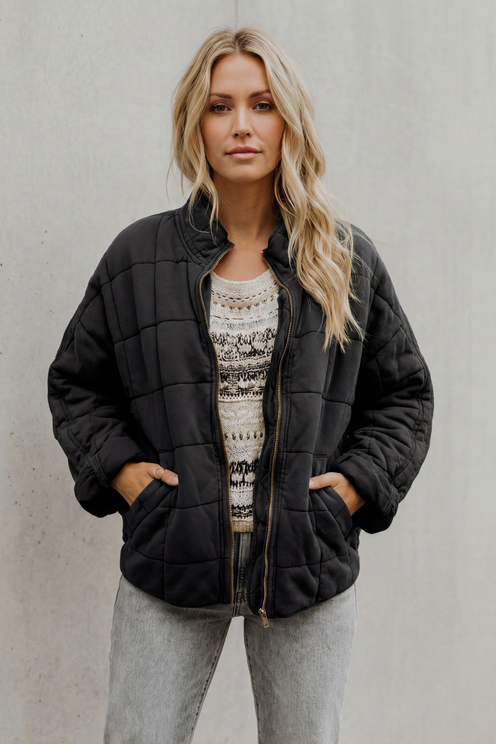 Black quilted women’s jacket with front zipper, stand collar, and elastic cuffs.