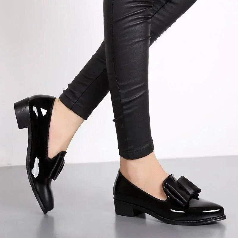 Black patent loafers with bow strap detail, worn with slim pants