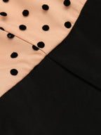 Polka-dot yoke seam joining black fabric on a wide-leg jumpsuit