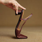 Brown leather pointed-toe slingback heels held upright, showing heel and strap.