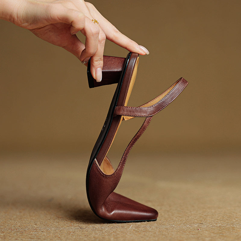 Brown leather pointed-toe slingback heels held upright, showing heel and strap.