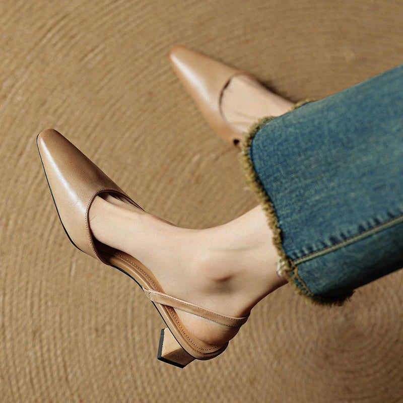 Beige leather pointed-toe slingback heels with low block heel and curved strap.