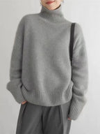 Grey turtleneck knit sweater with long sleeves and ribbed cuffs and hem.