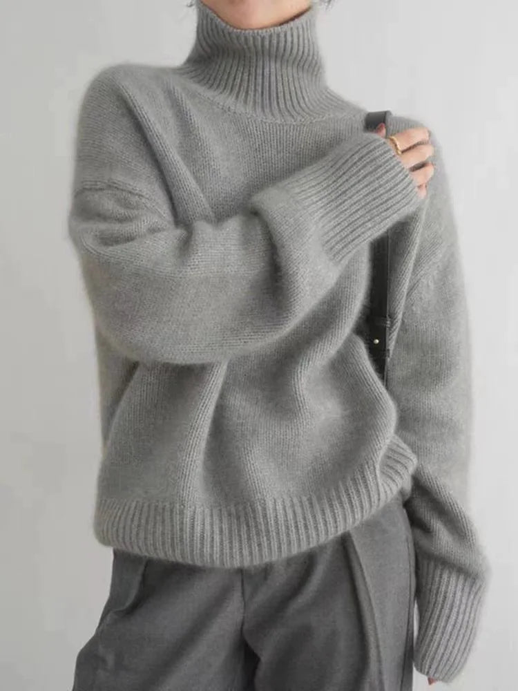 Grey turtleneck knit sweater with ribbed collar, cuffs, and slightly dropped shoulders.