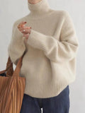 Beige turtleneck knit sweater with ribbed collar and wide long sleeves.