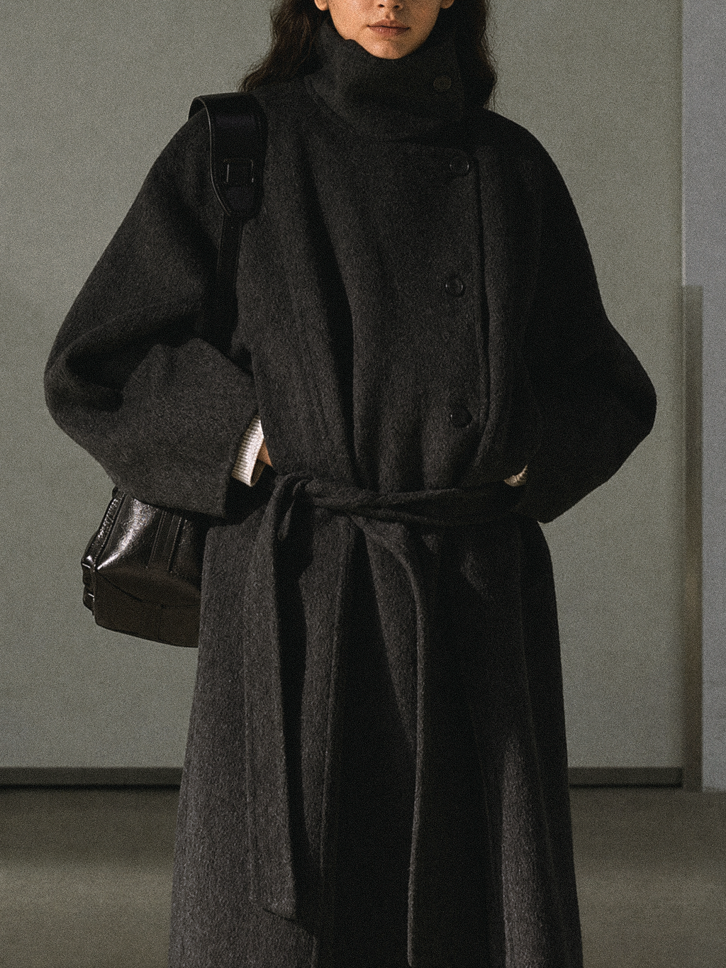 Dark gray wool long coat with stand collar and belt, close-up of torso