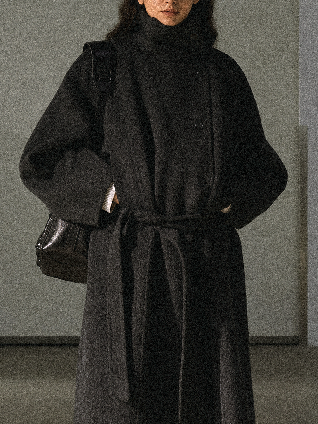 Dark gray wool long coat with stand collar and belt, close-up of torso