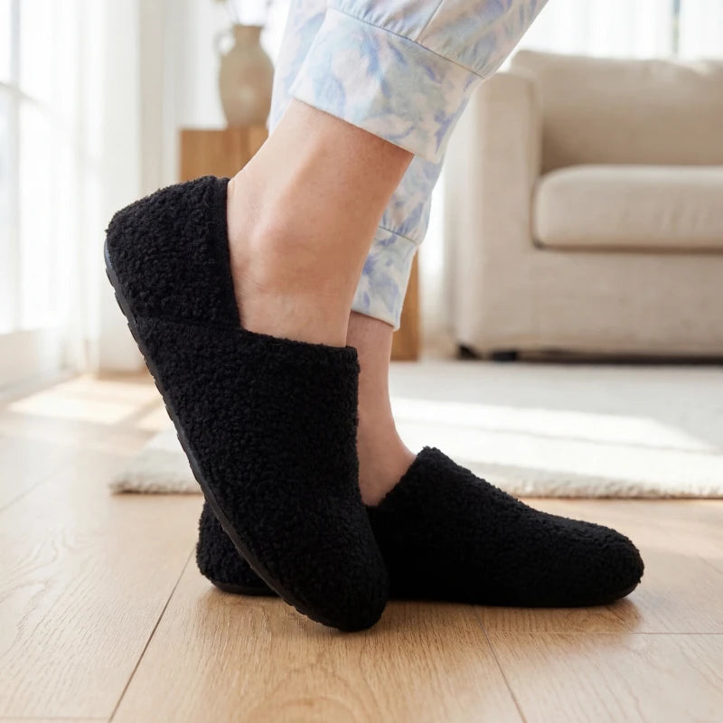 Black fuzzy slip-on barefoot slippers worn at home with soft cuff