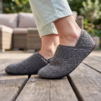 Grey textured slip-on barefoot slippers worn on wooden floor, soft plush upper