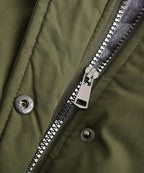 Close-up of olive green parka zipper and snap buttons with metal hardware