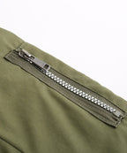 Close-up of olive green parka zipper with silver-toned pull and teeth