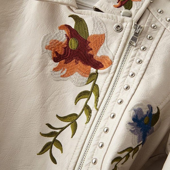 Pearl white leather jacket close-up with floral embroidery, silver studs, zipper