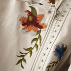 Pearl white leather jacket close-up with floral embroidery, silver studs, zipper