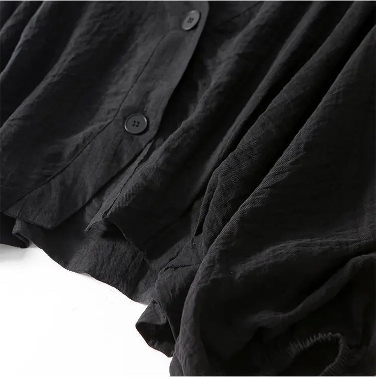 Black linen blouse close-up: textured fabric, button placket, draped hem