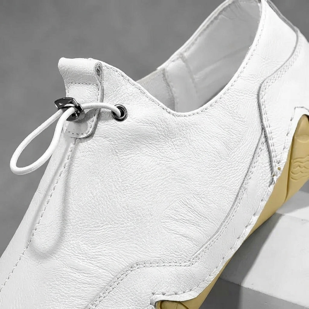 White leather casual sneaker side view with lace eyelets and smooth stitching.